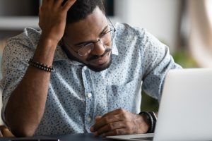Frustrated african American man experience problems working on laptop